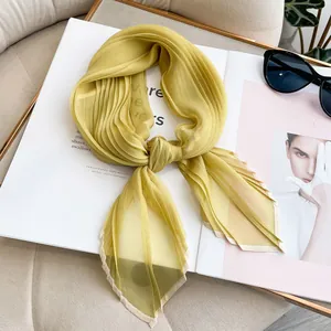 Detail of yellow pleated silk scarf tied in a bow on a fashion magazine with sunglasses