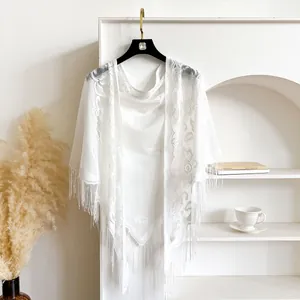 Elegant white lace shawl featuring floral embroidery and tassels on a stylish hanger