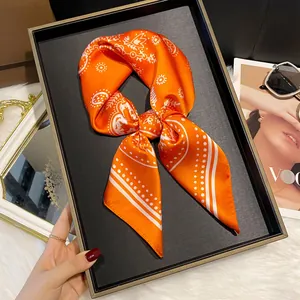 Close-up of elegant orange silk scarf with white paisley pattern tied in a bow