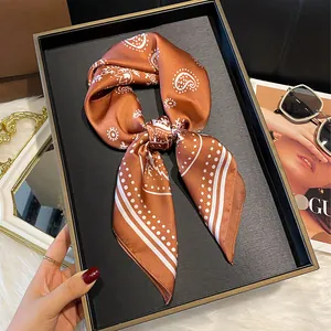 Elegant brown silk scarf with paisley pattern tied in a bow on a black leather tray