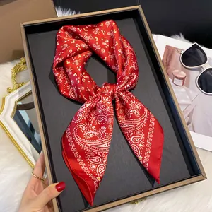 Détail d'un foulard en soie rouge à motif Paisley avec coutures fines sur un plateau