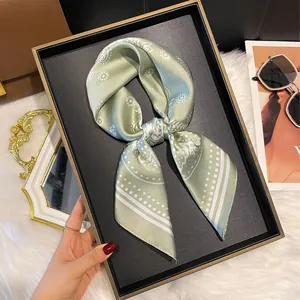 Elegant silk-like scarf with green geometric patterns and dots on a gold-rimmed tray