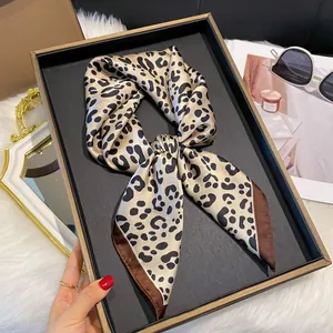 Détail d'un foulard en soie à imprimé léopard noué en nœud sur un plateau de mode
