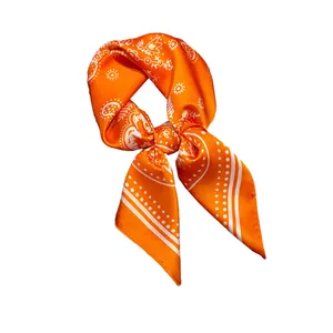 Orange silk square scarf with white paisley and polka dot print tied in a stylish knot