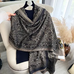 Dettaglio dell'elegante scialle jacquard nero e oro con motivi floreali e frange