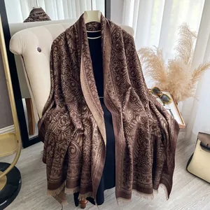 Dettaglio del motivo paisley jacquard e delle nappe su uno scialle marrone caldo