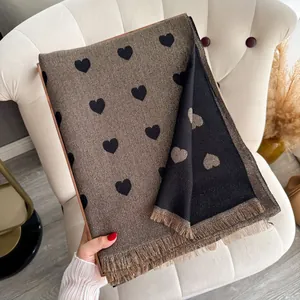 Detail of shimmering gold and black heart pattern scarf with fringe on a chair