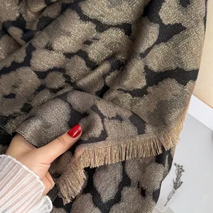 Détail de la texture léopard épaisse avec fil doré et franges sur le châle tissé