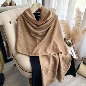 Dettaglio dello scialle jacquard paisley cammello con fili dorati e frange morbide