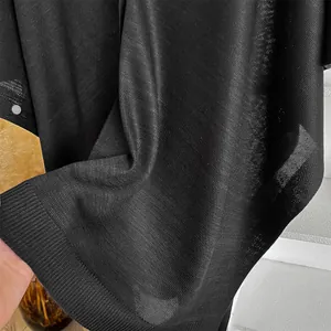 Gros plan sur la texture du châle en tricot noir avec ourlet côtelé et tissu doux
