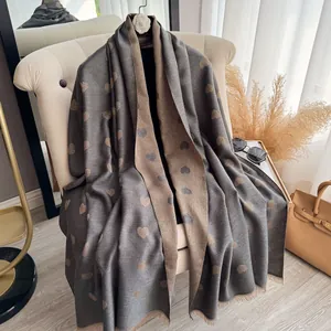 Double-sided jacquard heart scarf with tassels and metallic texture on a beige armchair