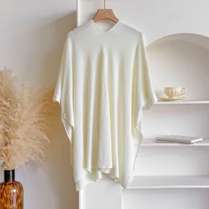 Détail d'un châle en maille blanc crème avec col en V et textures douces à bords côtelés
