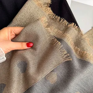Detailed view of jacquard heart pattern on dual-sided champagne gold and grey scarf