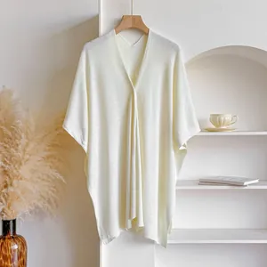 Détails de texture du châle en maille beige avec col en V et boutons délicats