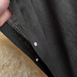Châle en tricot noir élégant avec des boutons-pression en métal argenté vus de près