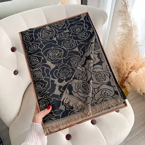 Detail van zwart-gouden rozen jacquard sjaal met franjes in een premium geschenkverpakking