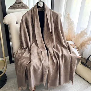 Details des hellbraunen Kaschmir-Schals mit goldener Jacquard-Struktur und Fransen