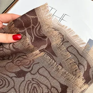 Macro-opname van koffiebruine jacquard sjaal met rozenpatronen en zachte franje rand