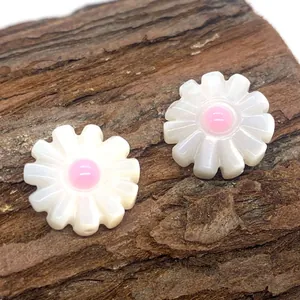 Macro shot of daisy-shaped natural white shell beads with pink floral centers on wood