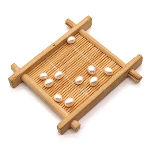 Macro detail of ten white rice-shaped freshwater pearls on a decorative bamboo tray