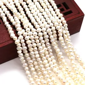 Macro view of white freshwater pearls in various sizes draped over a vintage wooden box