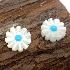 Macro detail of daisy-shaped white shell beads with blue centers on a natural bark backdrop