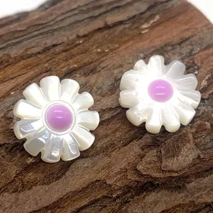 Macro view of shell flower earrings with white petals and purple centers on wood