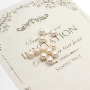 Macro shot of 12 natural white freshwater pearls with holes on a white invitation card