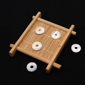 Détail macro de perles en nacre blanche de 15mm avec éclat naturel sur bois sombre