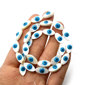 Macro detail of hand-held evil eye marquise shell beads for DIY jewelry making