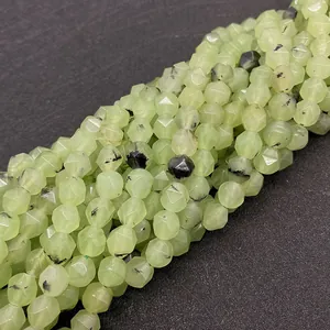Macro di perle in prenite naturale sfaccettate con inclusioni di aghi neri su sfondo scuro