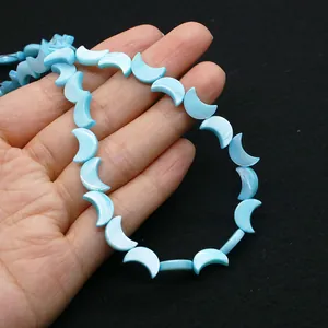 Gros plan de perles de nacre bleu clair en forme de croissant tenues à la main