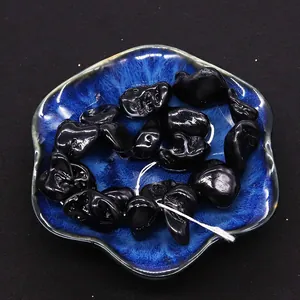 Detailed view of black irregular organic shell beads with high luster on a blue ceramic plate