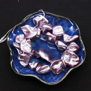 Detail of irregular lavender shell beads with metallic luster in a blue ceramic dish