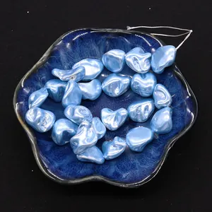 Close-up of light blue irregular natural shell beads with soft luster in a blue dish