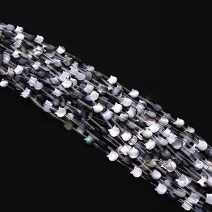 Détail macro de perles en nacre noire en forme de chat avec des reflets irisés