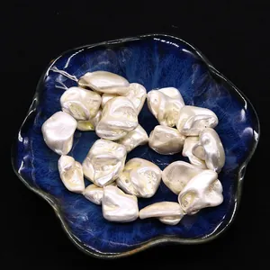 Macro detail of irregular baroque shell beads with iridescent luster in a blue bowl