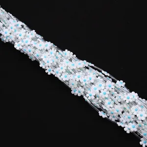 Macro shot of 12mm white shell flower beads with blue centers on transparent cord