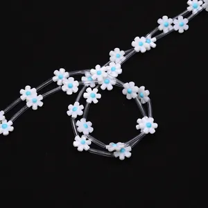 Close-up of white shell flower beads with blue centers and clear connector tubes
