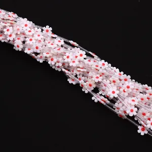 Macro shot of 12mm white shell flower beads with red centers on black background