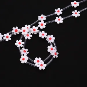 Macro detail of 12mm white shell flower beads with red centers and clear tube spacers