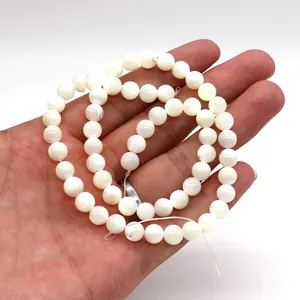 Polished natural white mother of pearl round beads held by hand for jewelry DIY
