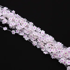 Macro detail of 12mm natural white shell flower beads with purple centers for DIY jewelry