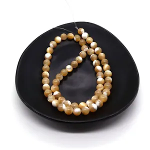 Polished champagne and cream natural shell beads on black ceramic plate for DIY jewelry