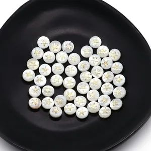Detail of natural white shell beads with golden star patterns on a black ceramic tray