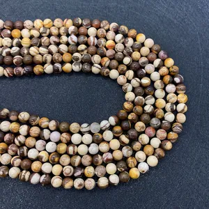 Détail macro de perles rondes en pierre zèbre naturelle aux textures polies marron et beige