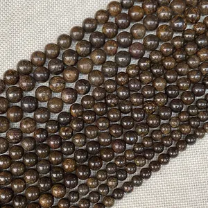 Cuentas redondas de piedra natural marrón oscuro sobre fondo de tela beige texturizada