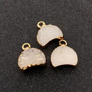 Vue macro de trois pendentifs en cristal naturel en forme de croissant dorés à l'or