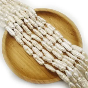 Fili di perle d'acqua dolce barocche bianche su un vassoio di legno rotondo, perle naturali