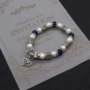 Vista dettagliata di perle bianche, perline blu e ciondolo a cuore in argento sul bracciale